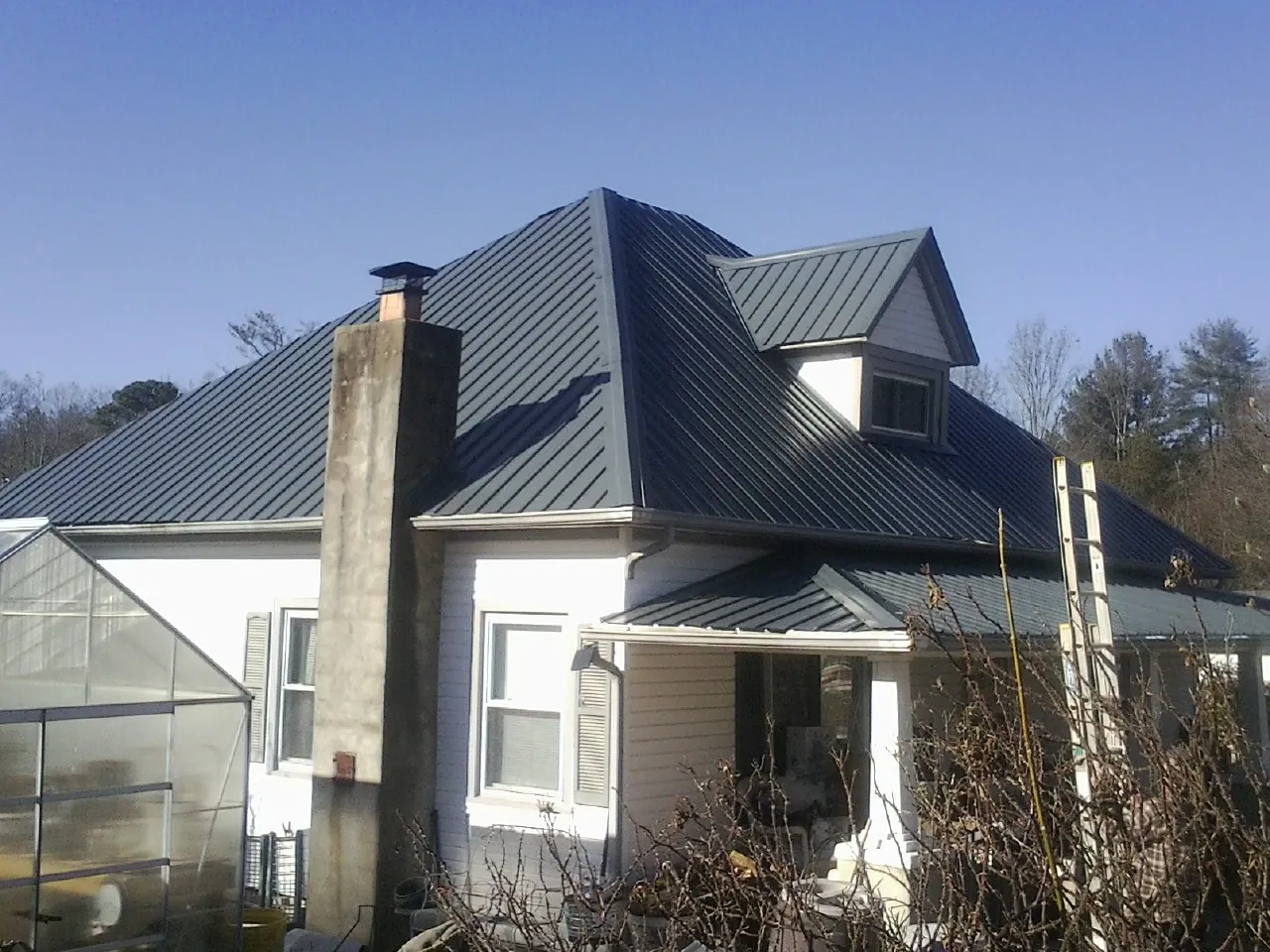 Dark blue standing seam metal roof on a white farmhouse with dormer — Slate & Tile Roof Repair by Roofing Brothers in Winfield