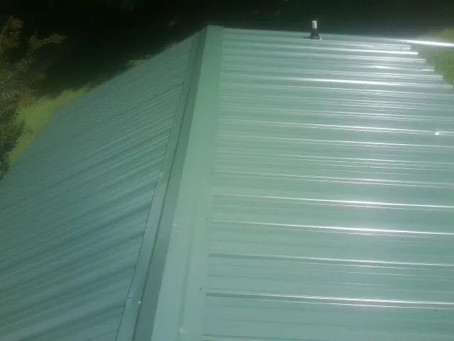 New green metal panels meeting at the ridge of a roof — Flat Roof Repair work by our crew in Winfield