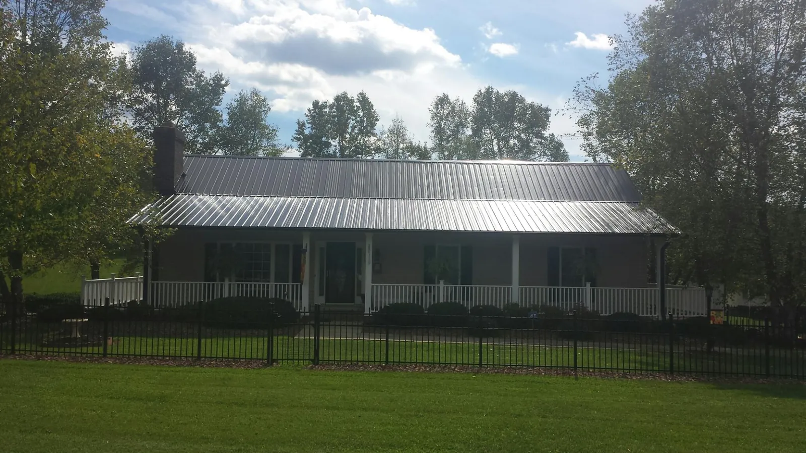 Gray metal roof on a brick ranch with a full width front porch — Gutter Guard Installation work by our crew in Winfield